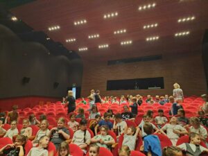 dzieci siedzą na widowni w oczekiwaniu na rozpoczęcie przedstawienia