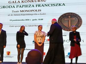 kardynał Konrad Krajewski wręcza stojącej przed nim uczennicy medal